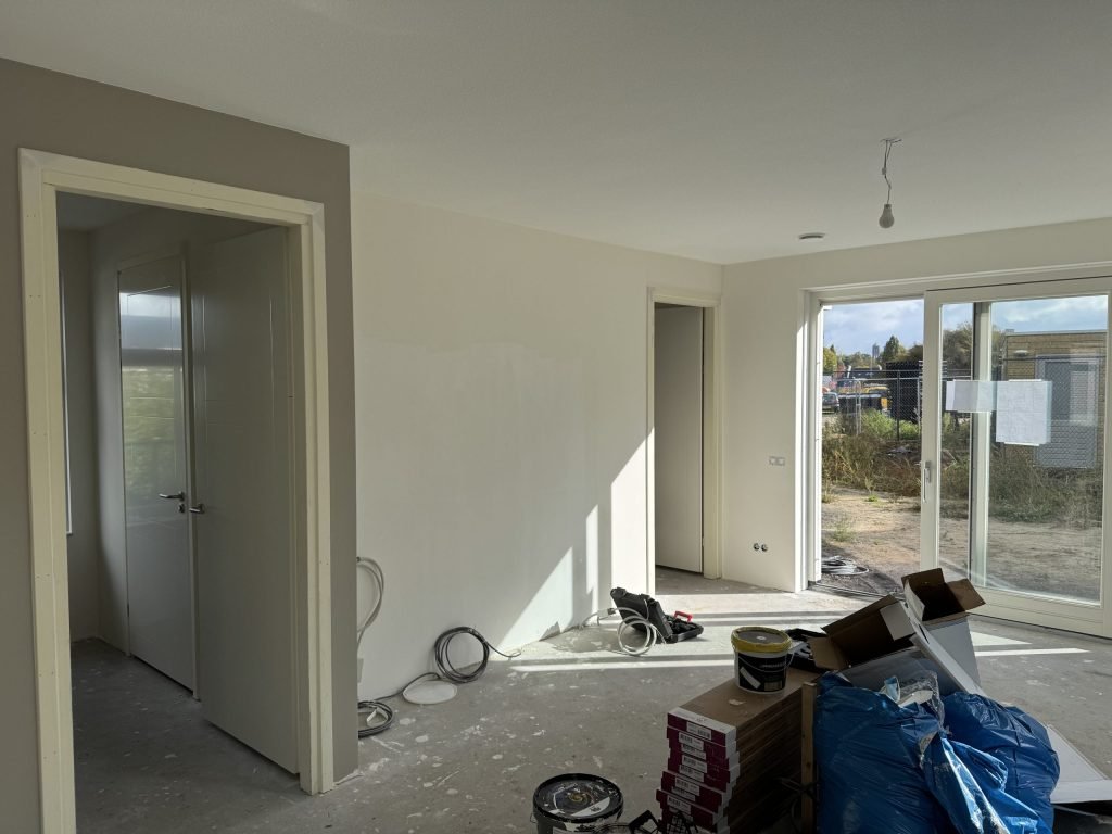 Woonkamer met lichte wanden, twee binnendeuren en schuifpui, klaar voor de laatste sauslaag